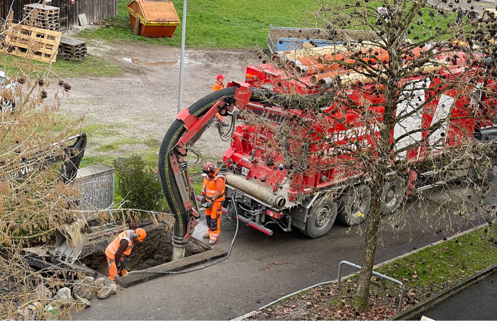 I observed a vacuum digger today. I somehow find them fascinating (the image shows a red vacuum digger and two workers digging a hole in a street).
