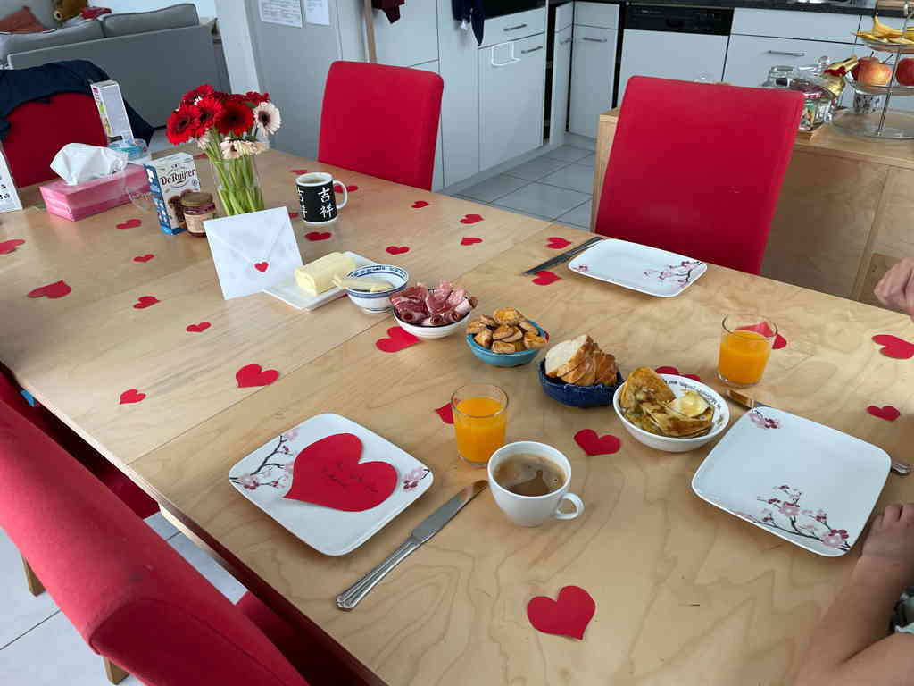 The nicely decorated table for mothers day. With the breakfast ready. Most of the work done by our daughter (with some help from me).
The table is decorated with red hearts and the food is lined up in the middle (egg, bread, cookies, meat, cheese, butter).
