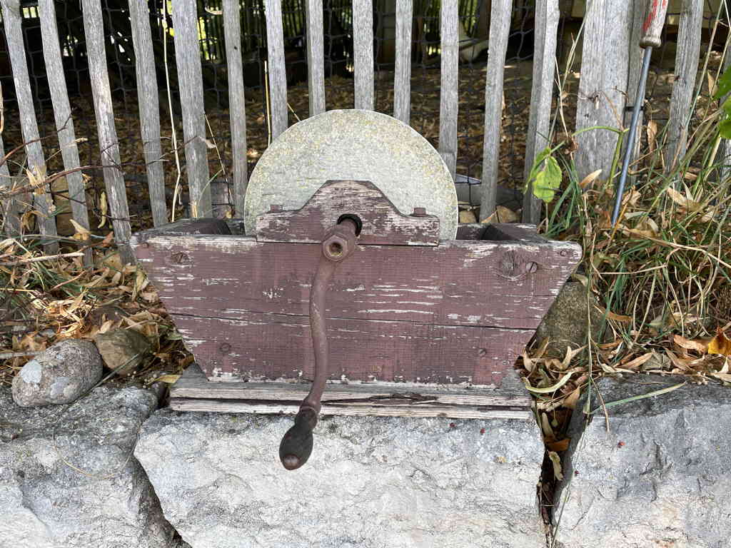 In the center is an old sharpening stone on a stone wall.