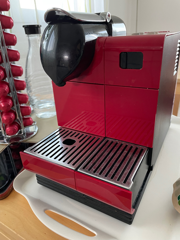 A close-up of our Nespresso coffee machine. It has a red body with some black accents.