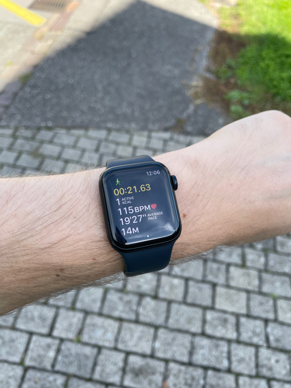 A picture of my Apple Watch showing the walking workout screen. The watch is on my left arm which I hold diagonally across the image. In the background the outside floor is visible with some interesting shadows cast.