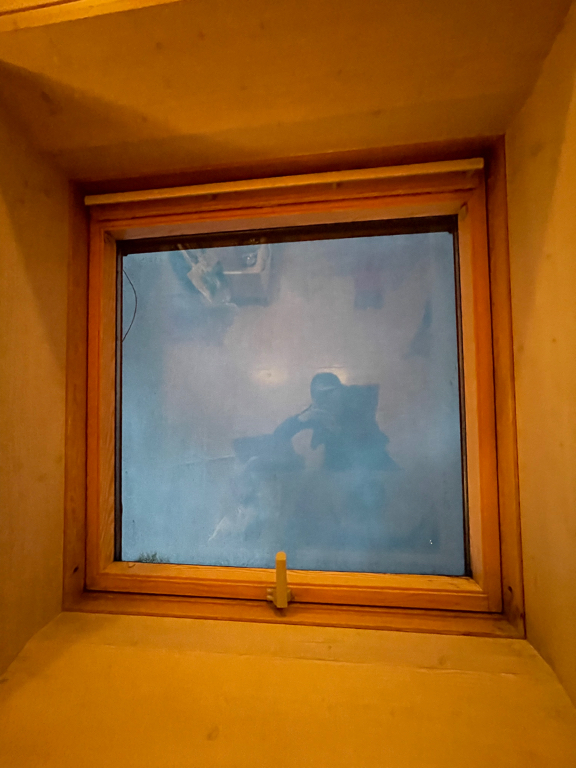 A close up photo of our skylight, with a faint reflection of myself in the glass, because it is dark outside and bright inside.