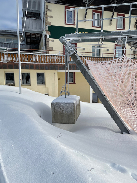 A concrete counter weight for a ski lift. Covered in hoarfrost. In the background is a restaurant building.