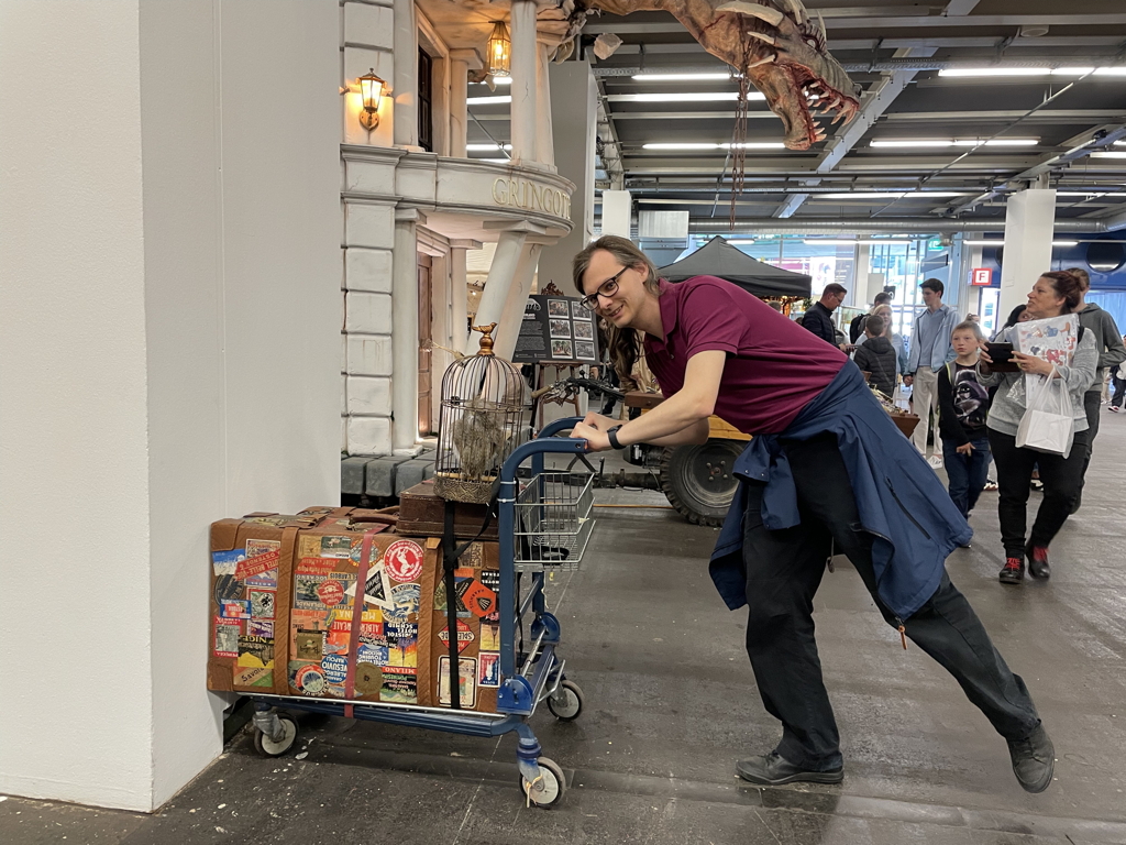 The trolley from Harry Potter is placed against a pillar, with me holding it.
