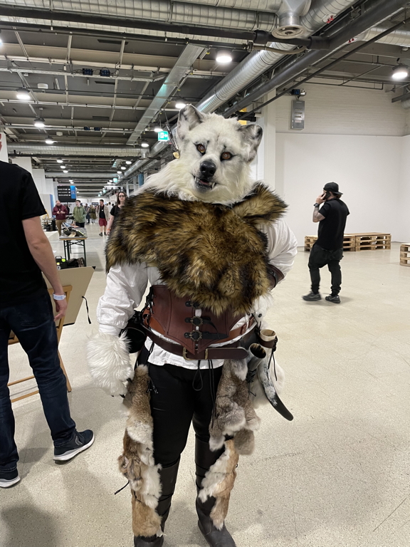 A cosplay of a wolf with fur and a realistic looking animal head.