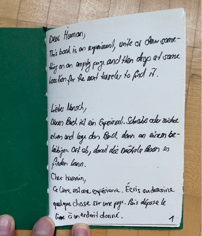 The introduction to the book. The text in the image reads: “Dear Human, This book is an experiment, write or draw something on an empty page and then drop the book at some location for the next traveler to find it.”