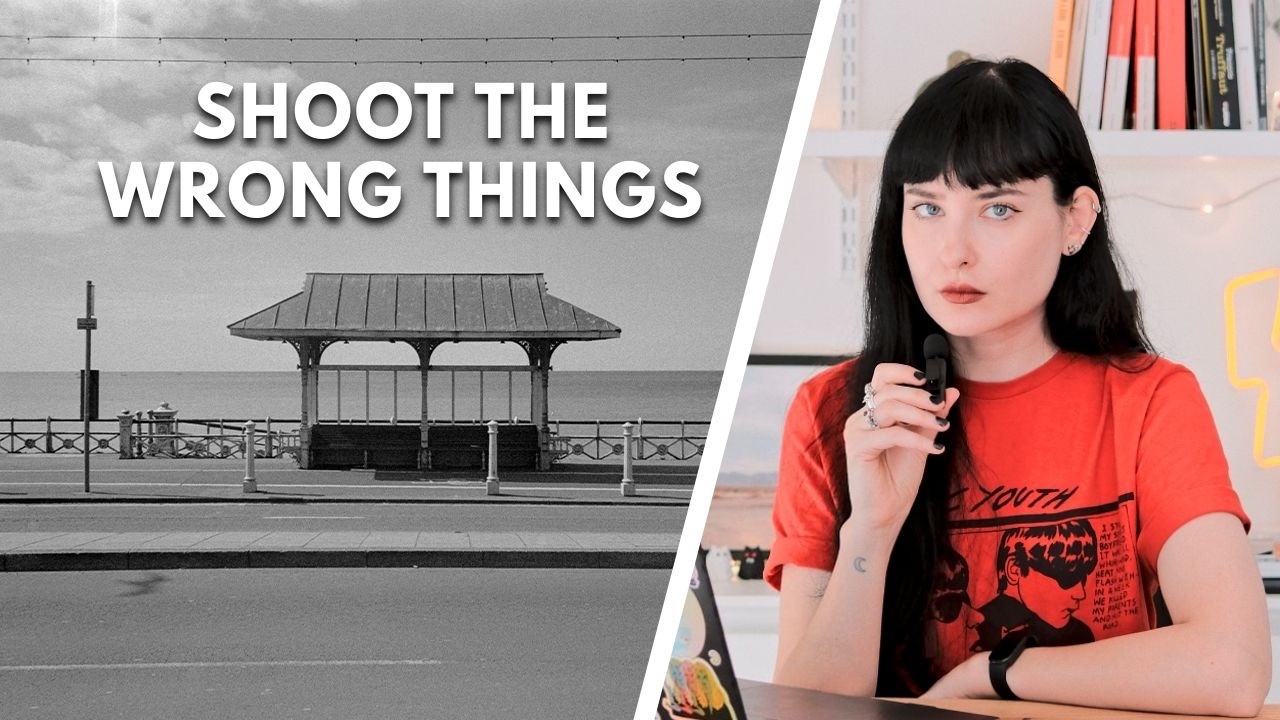 The YouTube video thumbnail is split into two sections. On the left, there’s a black and white image of a seaside shelter overlooking the ocean, with the text “SHOOT THE WRONG THINGS” in bold white letters. On the right, there’s a color image of a person with dark hair wearing a red T-shirt, sitting at a desk, speaking into a microphone. The background includes a bookshelf and string lights.